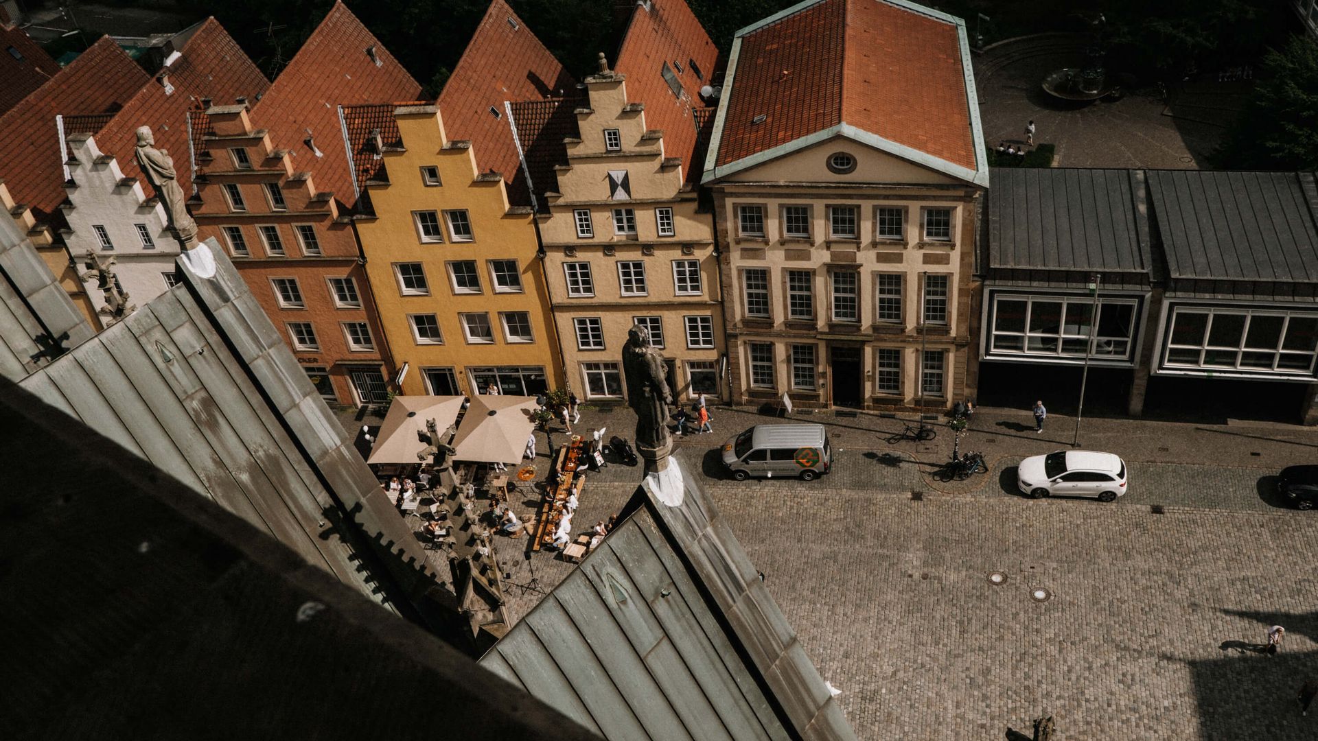 Blick auf den Platz mit farbenfrohen Giebelhäusern und Cafétischen aus der Höhe der Marienkirche.