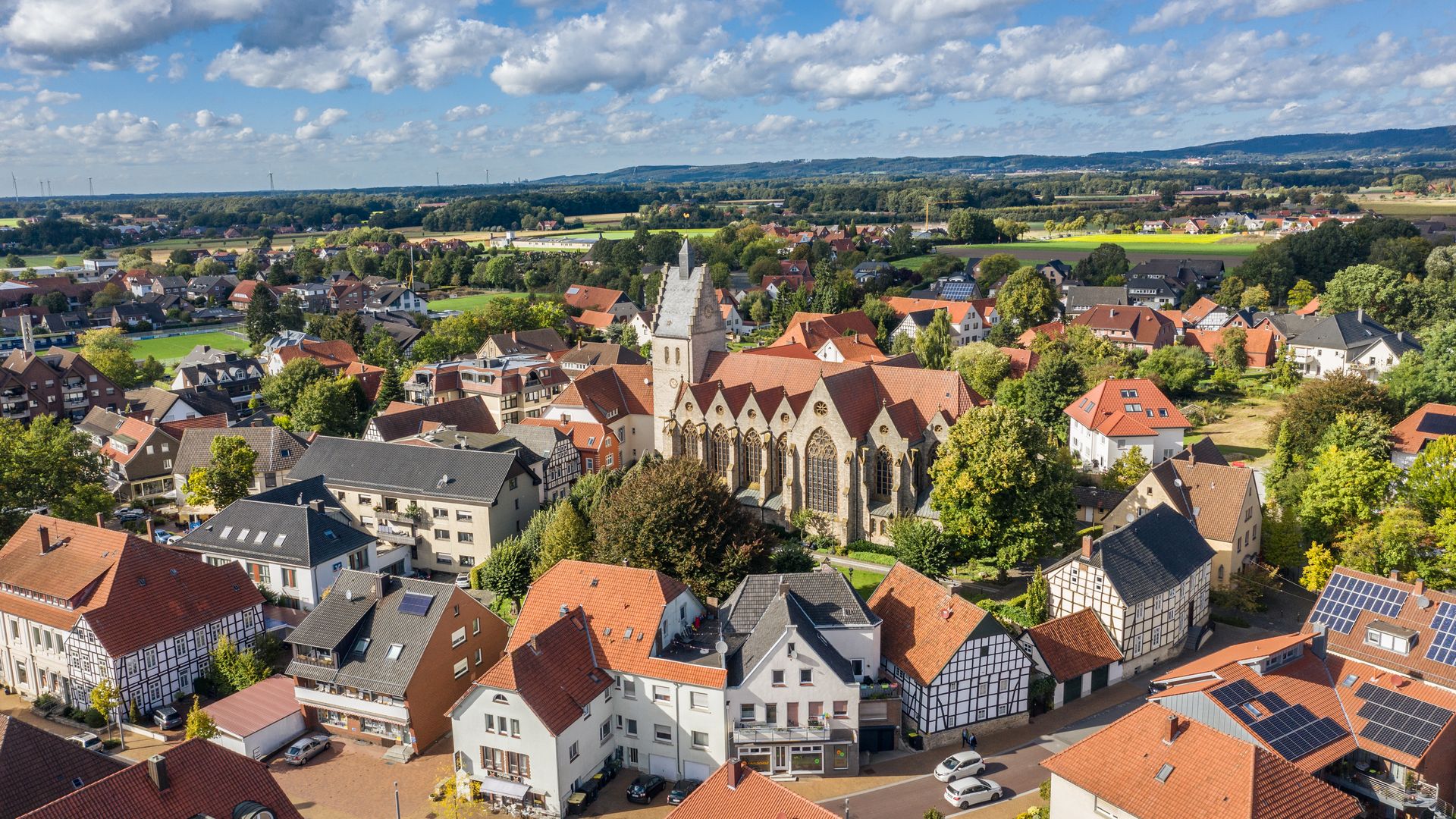 Kirche im Zentrum einer beschaulichen Ortschaft, umgeben von Häusern und grüner Landschaft.