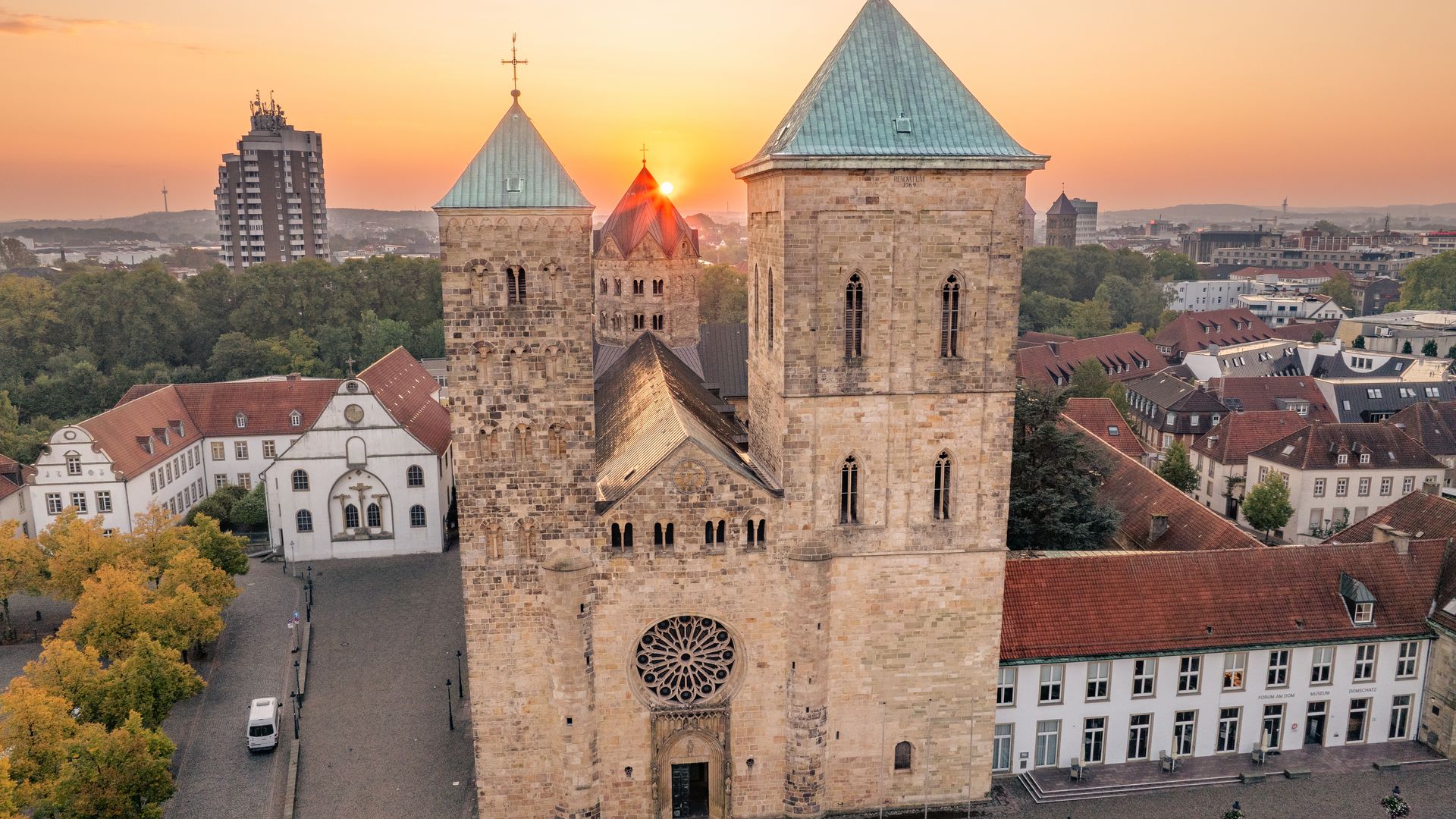 Luftaufnahme der St.-Petri-Domkirche in Osnabrück bei Sonnenuntergang, umgeben von Gebäuden.