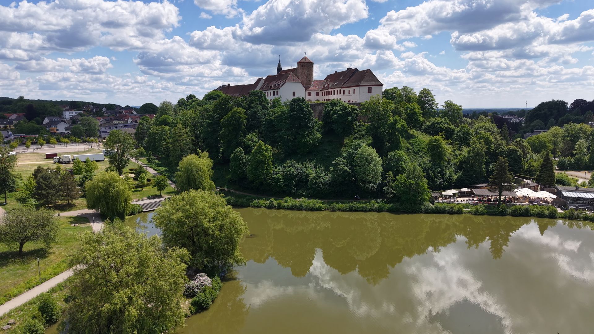 Schloss Iburg mit dem Charlottensee im Vordergrund, eingebettet in die grüne Landschaft rund um Bad Iburg.