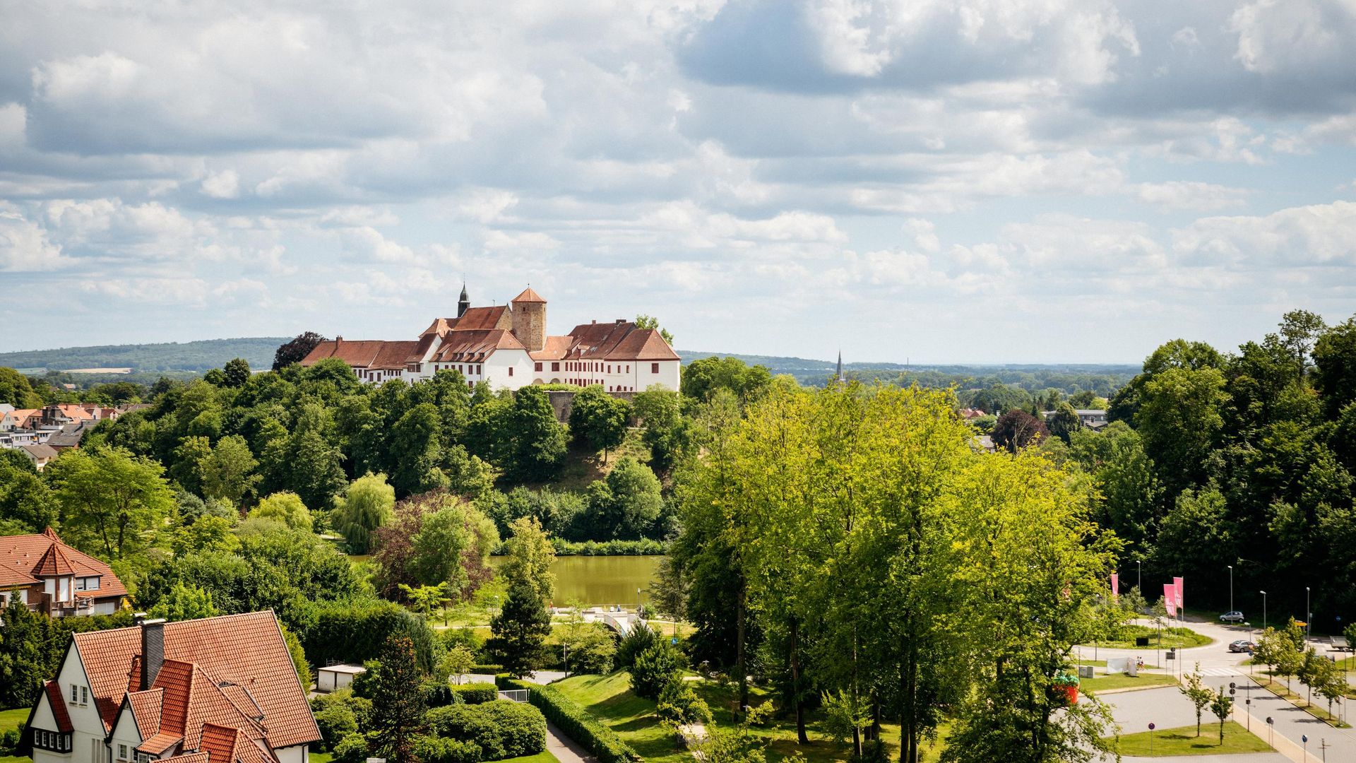 Blick auf eine historische Burg auf einem bewaldeten Hügel mit umliegender Landschaft.