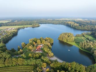 Luchtfoto van een meer met beboste oevers, een eiland en een klein stuk strand.