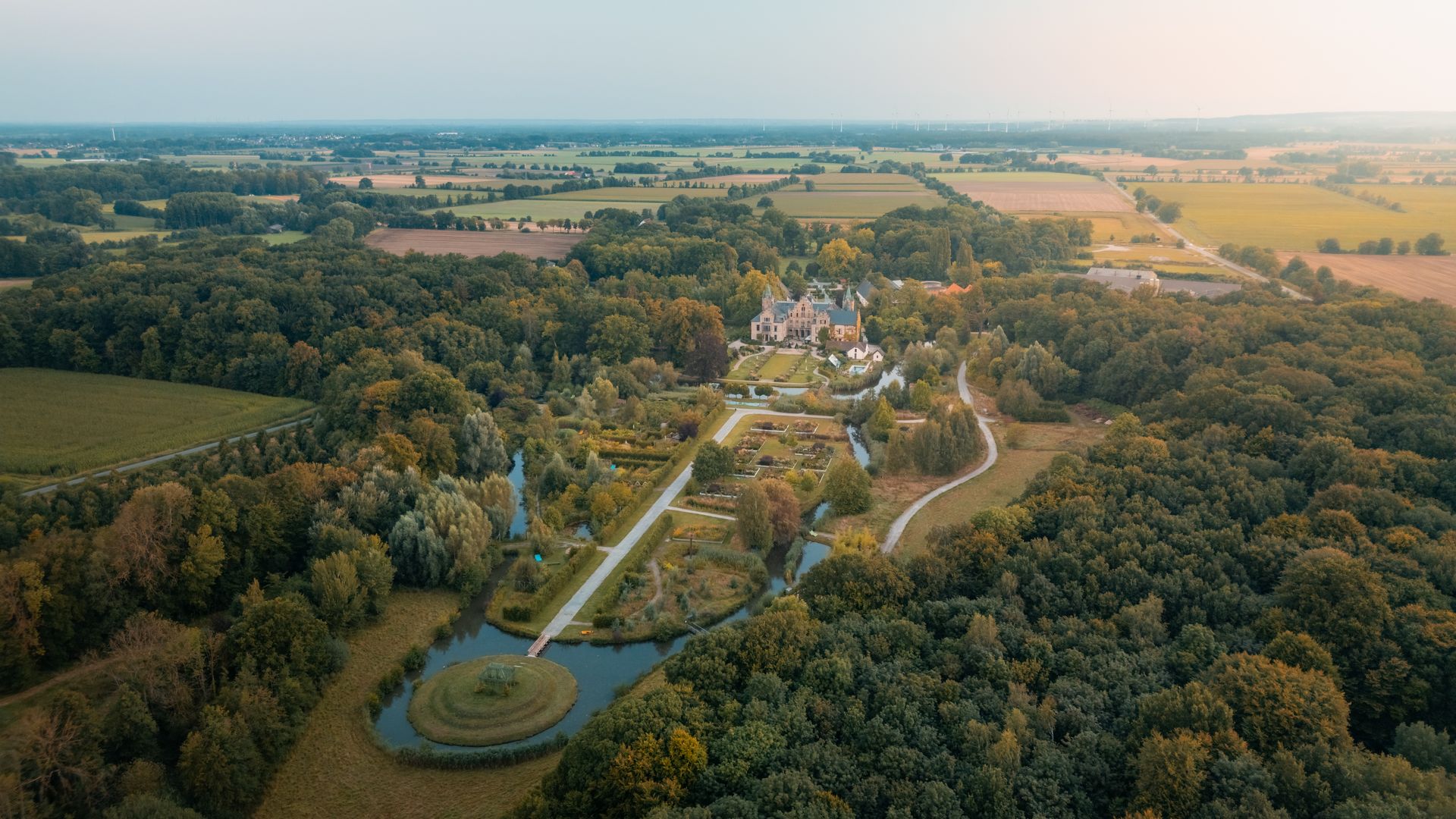 Luftaufnahme von Schloss Ippenburg umgeben von weitläufigen Gärten und bewaldeter Landschaft.