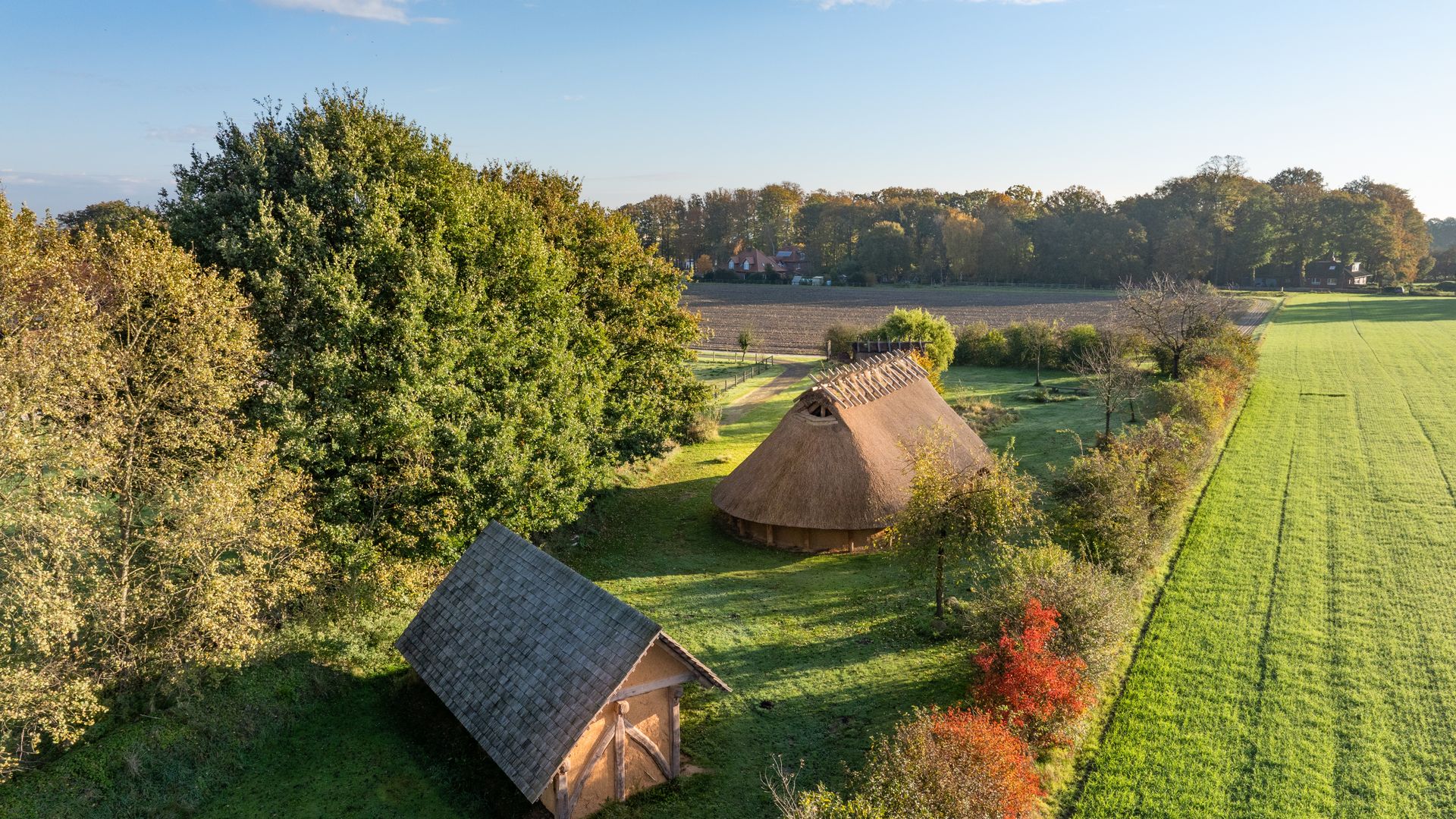 Luftaufnahme zweier traditioneller Häuser in grüner Landschaft, umgeben von Bäumen und Feldern.