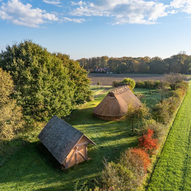 Luftaufnahme zweier traditioneller Häuser in grüner Landschaft, umgeben von Bäumen und Feldern.