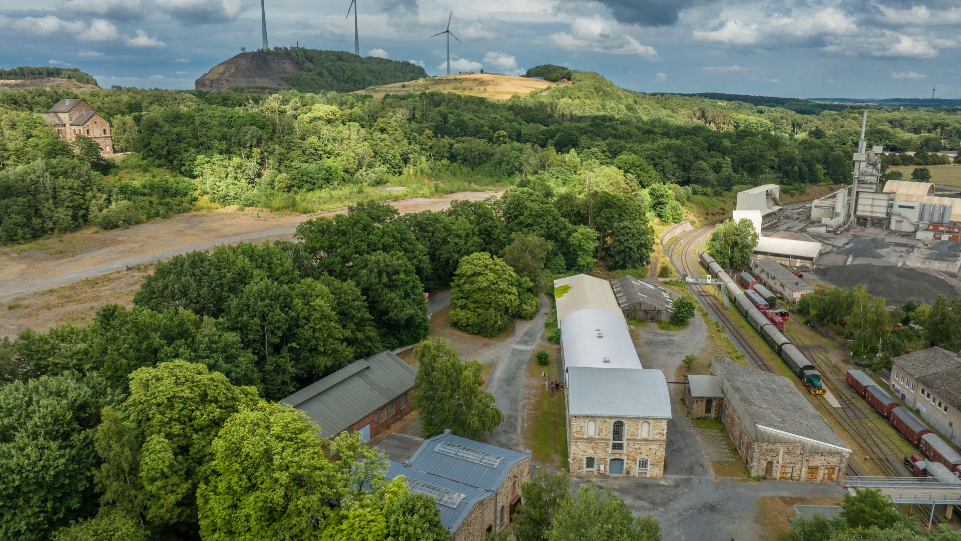 Industriegelände am grünen Piesberg, Osnabrück, mit Windkraftanlagen und historischer Architektur.
