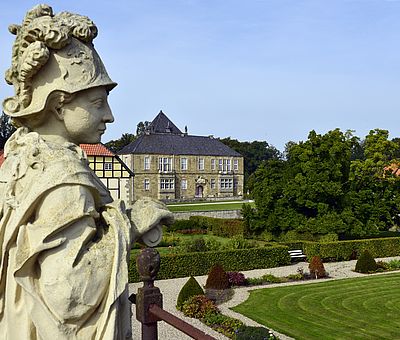 Sandsteinfiguren blicken auf die gelungene Wiederherstellung des Barockgartens von Schloss Gesmold bei Melle. In der ehemaligen Orangerie befindet sich heute ein Bio-Café.