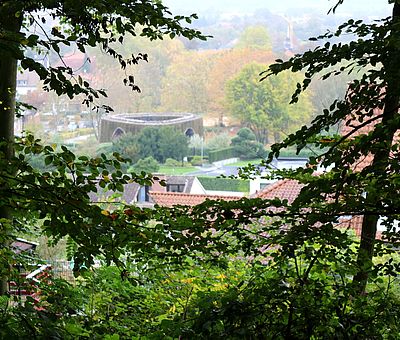 Eine Wanderung über die Gesundheitspfade in Bad Essen bringt den Körper in Schwung und man bleibt fit. Auf diesem Bild sieht man zwischen den herbstlichen Bäumen hindurch auf die SoleArena im Kurpark. Dort könnt ihr die gute Bad Essener Sole inhalieren und so Erkältungen vorbeugen.