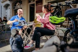 Ein Mann und eine Frau genießen Kaffee im Freien vor einem Café, mit Fahrrädern im Vordergrund.