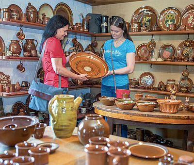 Auf den Regalen in der großen Halle stehen viele erdfarbene Näpkes, Kümkes, Tabakspötte. Zusammen mit Spielzeugnachtigallen aus Ton ist dieses traditionelle, erdfarbene Geschirr mit Pünktchen oder Streifen verziert typisch für die Arbeiten der Pottbäcker Niehenke