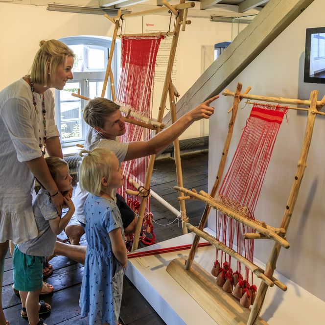 Eine Familie betrachtet traditionelle Webrahmen in einem Museum.