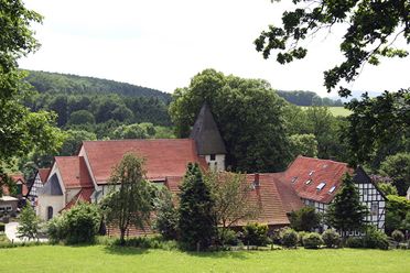 Bissendorfer Kirchburg in Holte mit Fachwerkgebäuden und Kirchturm in grüner Umgebung.